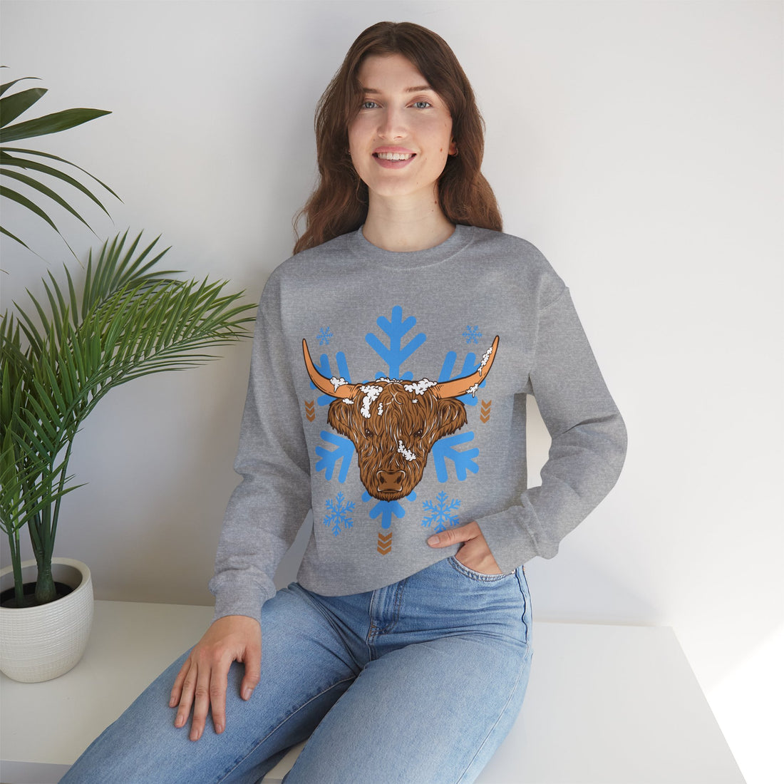 Shaggy brown Highland cow head centered over large light-blue snowflakes, color option