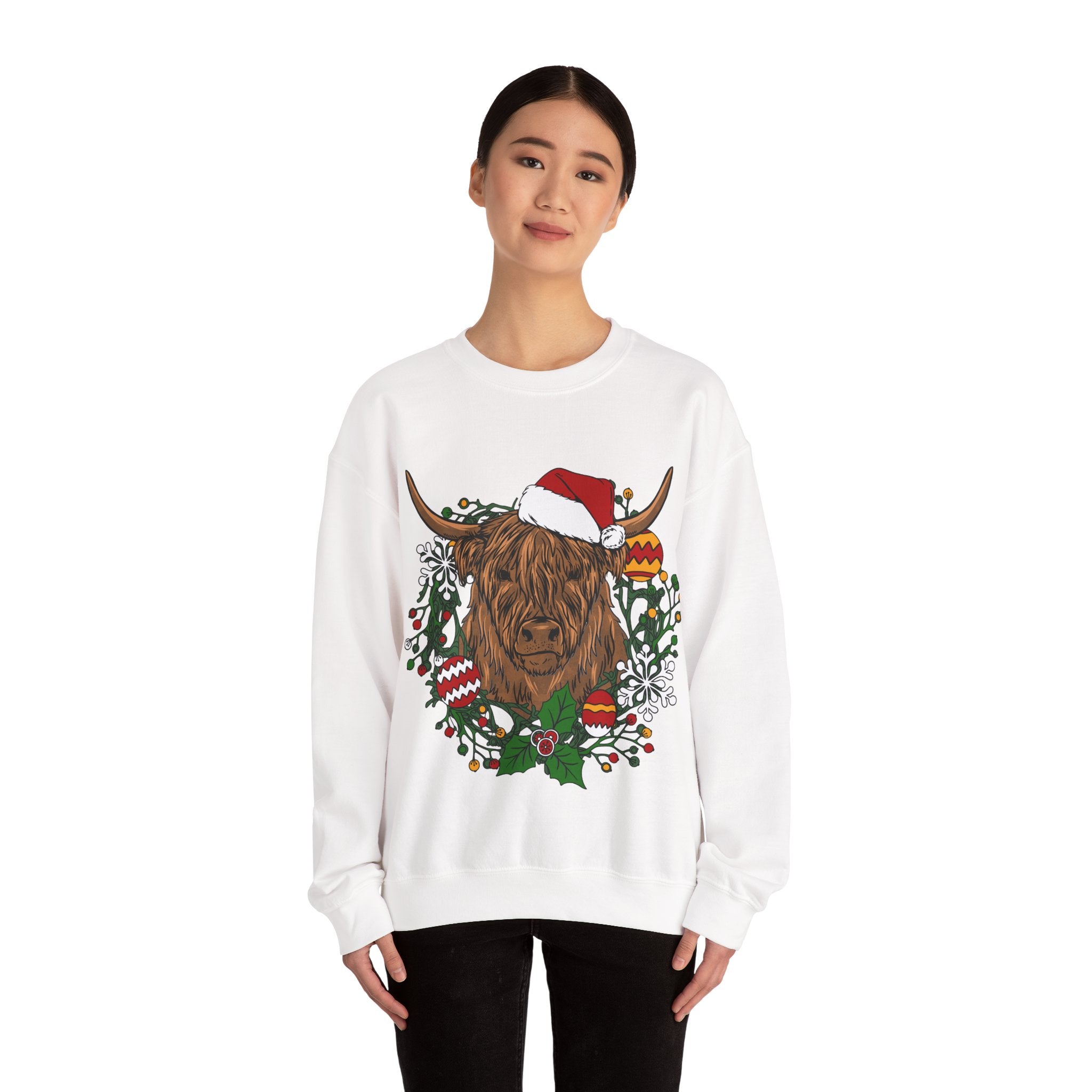 Shaggy Highland cow wearing a Santa hat framed by a holly and ornament Christmas wreath, alternate view