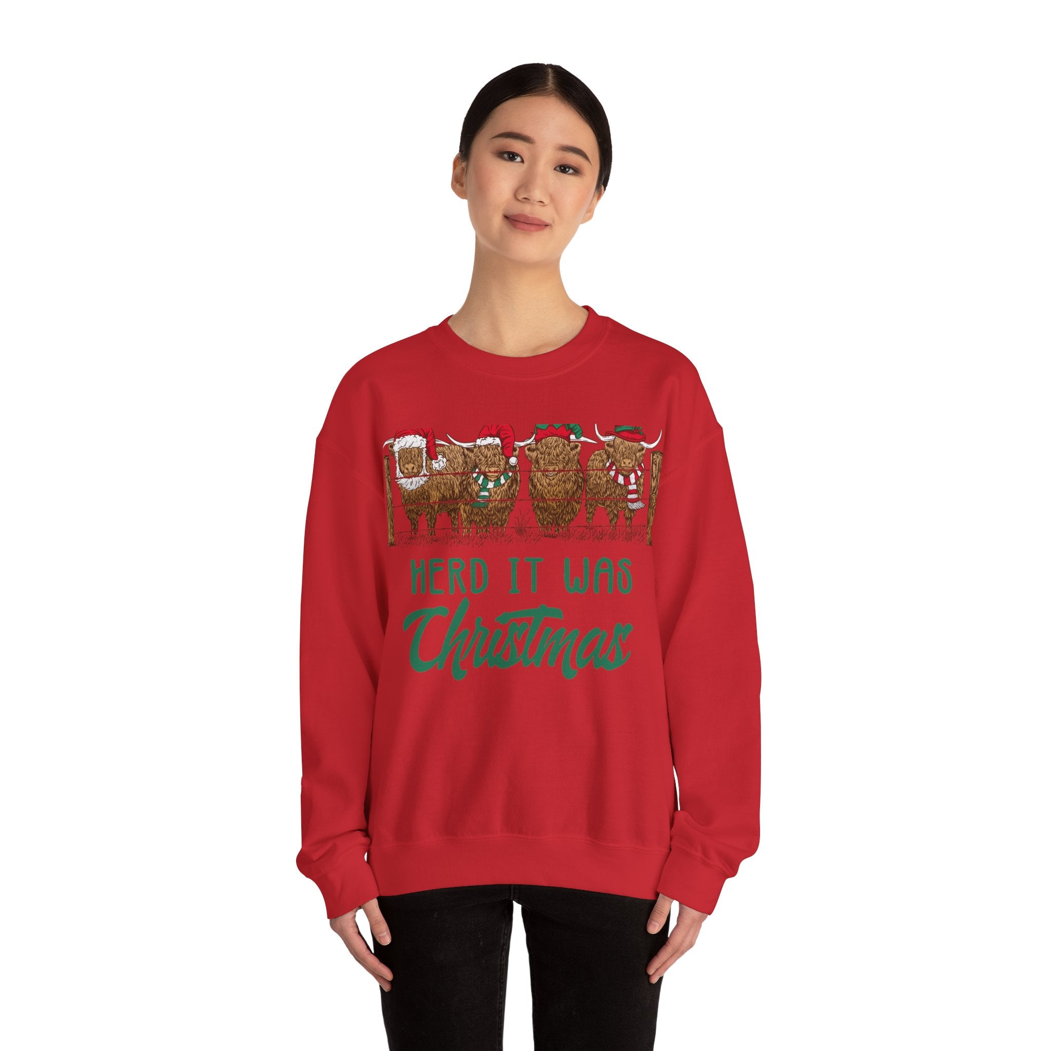 Four Highland cows lined up behind a wooden fence wearing Santa and elf hats with Herd It Was Christmas lettering in green and red, color option