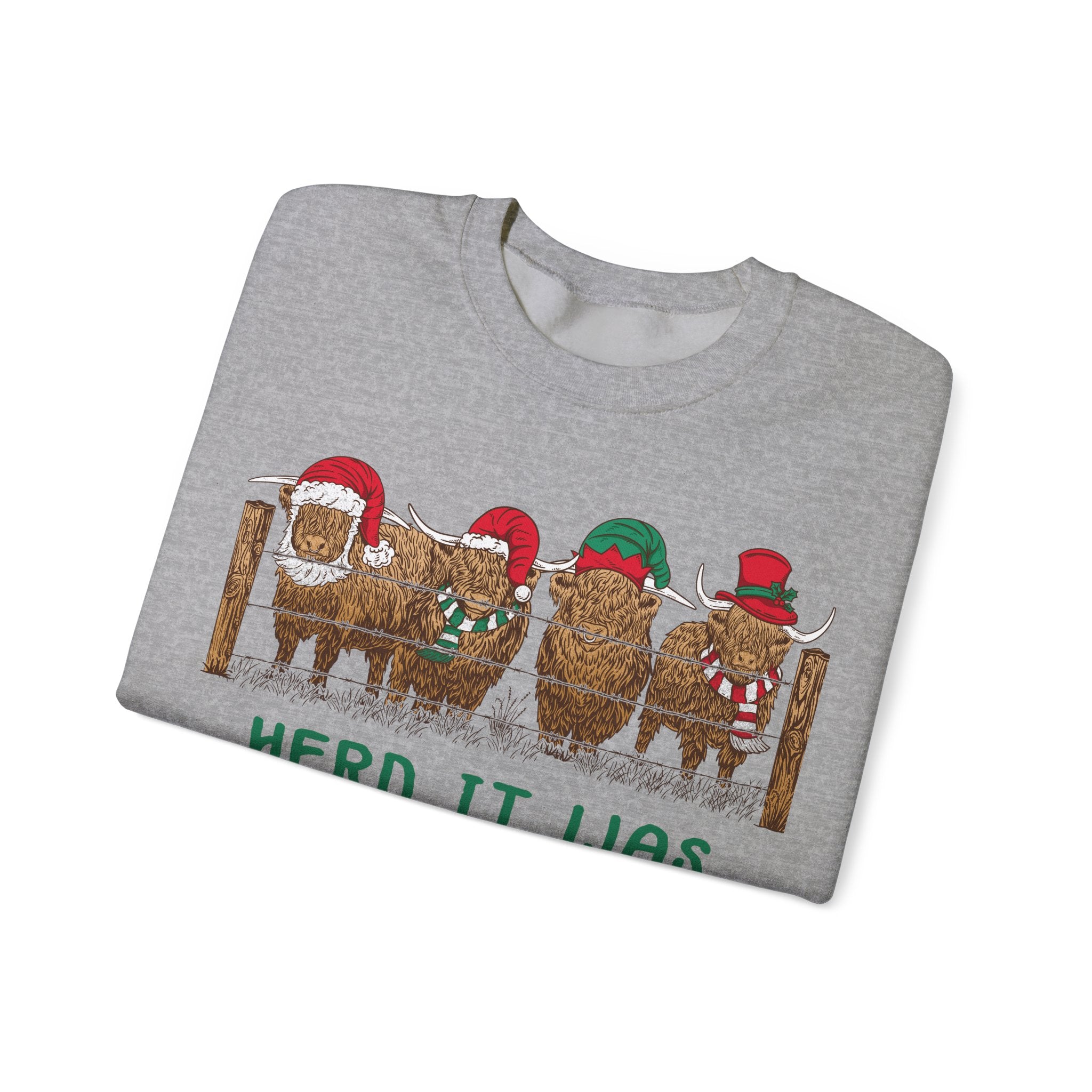 Four Highland cows lined up behind a wooden fence wearing Santa and elf hats with Herd It Was Christmas lettering in green and red, alternate view